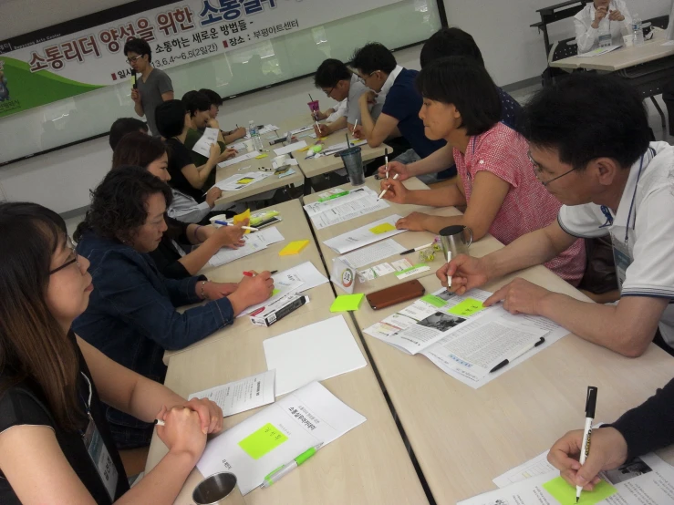 a number of people sitting at a table with papers and pens