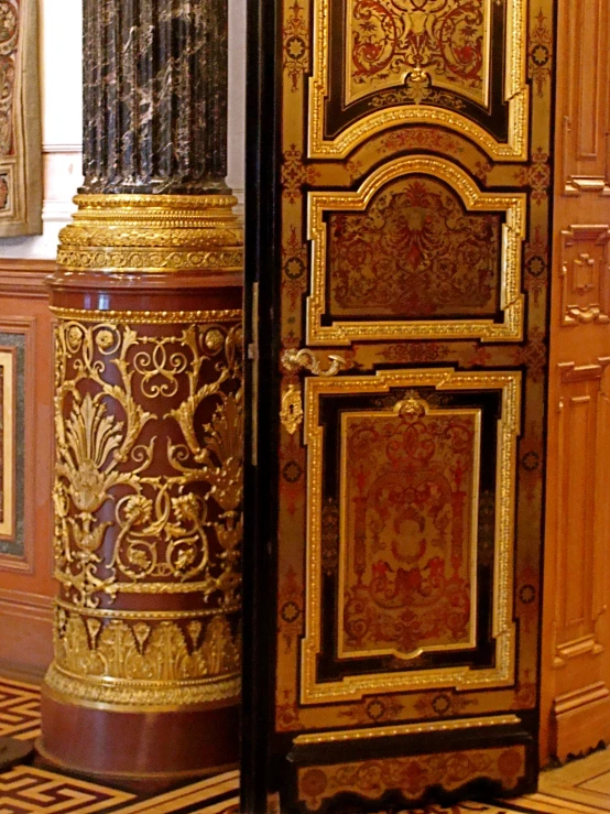 a gold and red ornate cabinet is standing next to a picture of a bird on the armoire