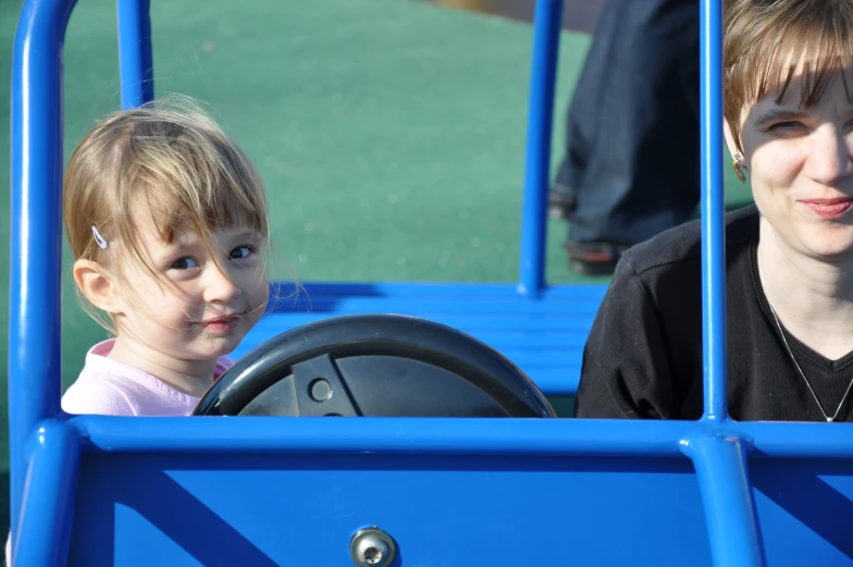 two young children are sitting inside of a blue bus