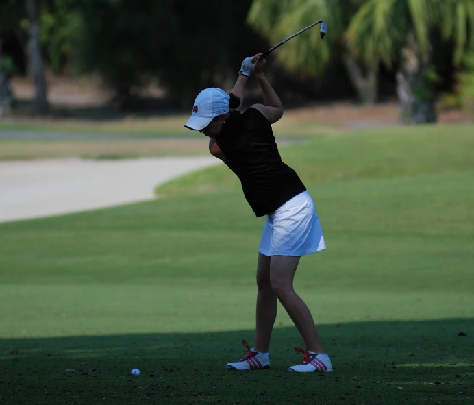 a woman in black shirt and white skirt playing golf