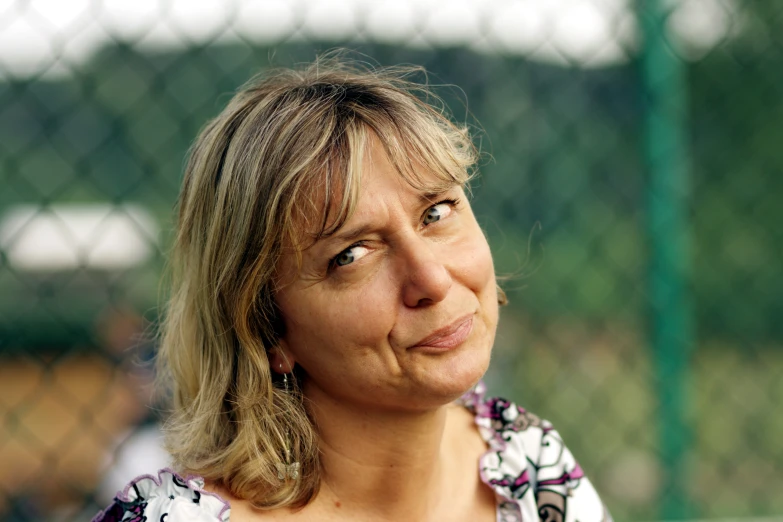 a close up of a woman looking out a fence