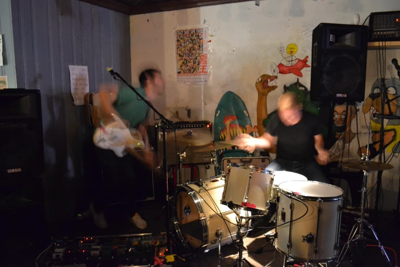 two men play the drums while another person sings