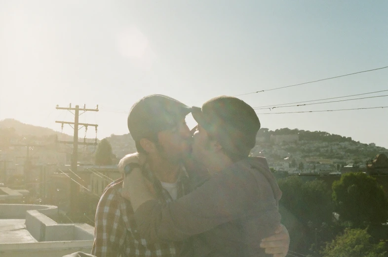 two young men hug outside in the sun