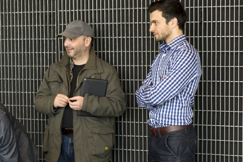 two men wearing hats looking at another man using his cell phone