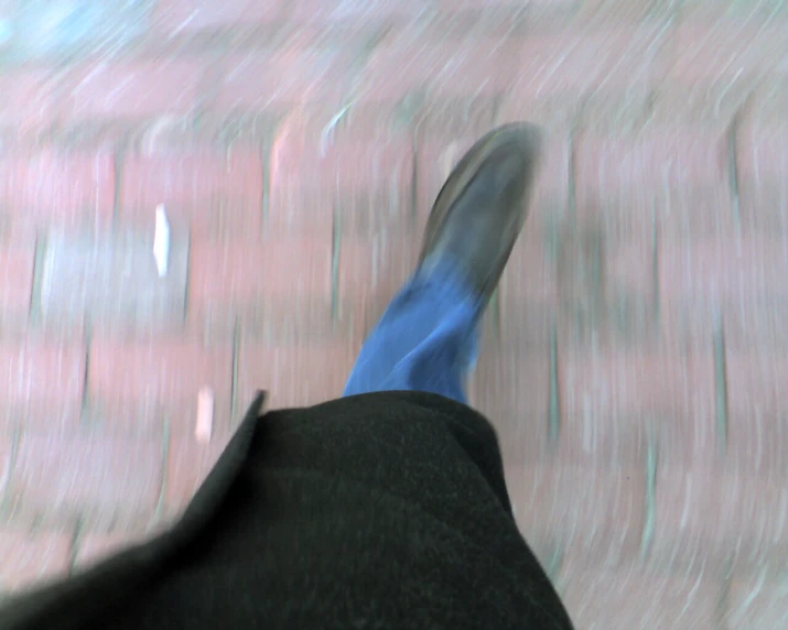 a man with blue feet in front of a brick wall