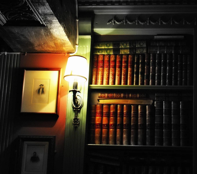 an old wall light sitting between a bookshelf and a lamp