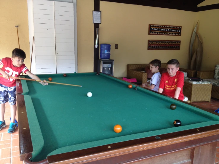 four children in the room playing pool