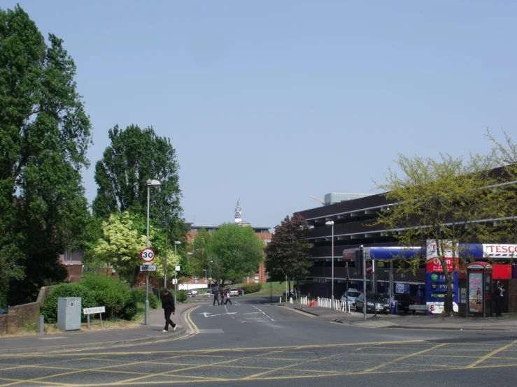 a person is crossing a street in the middle of the day