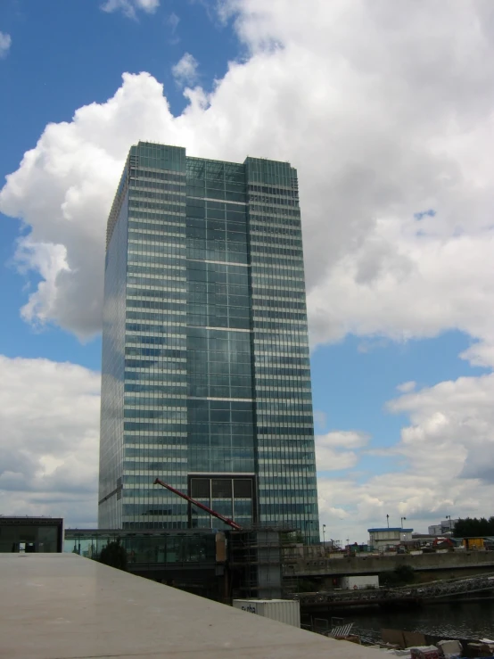 an office building next to a river under a cloudy sky