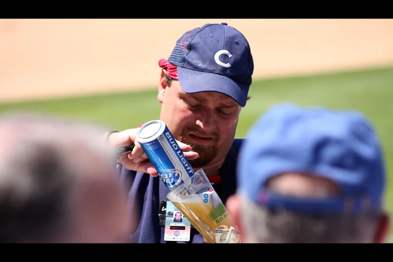 a baseball player holds up a can of beer