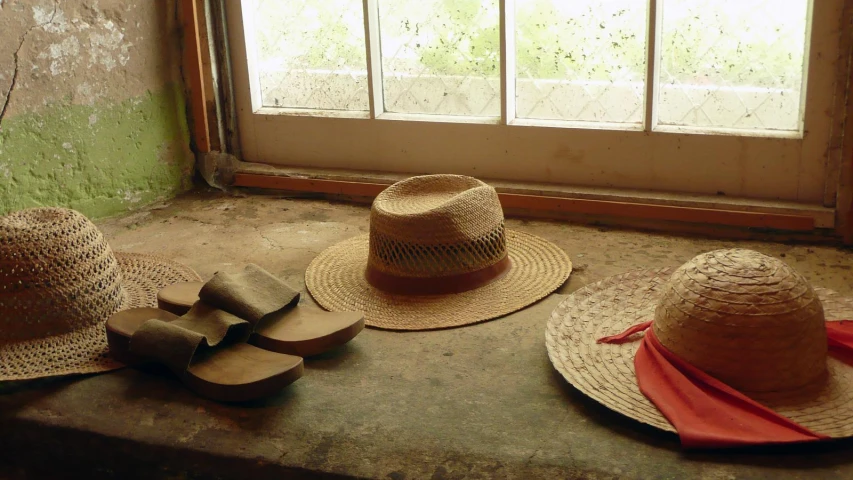 three hats are sitting on the ground in front of a window