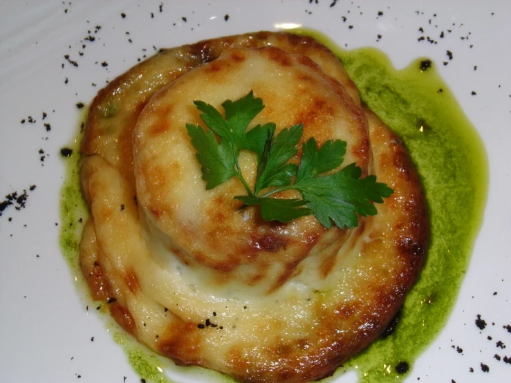 food item with green sauce, white plate on table