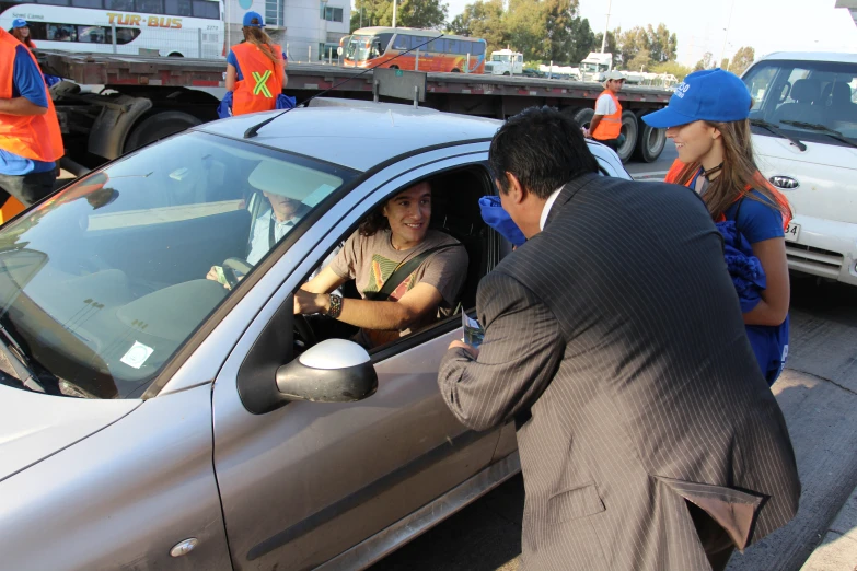 the car driver is talking to the passenger on the street