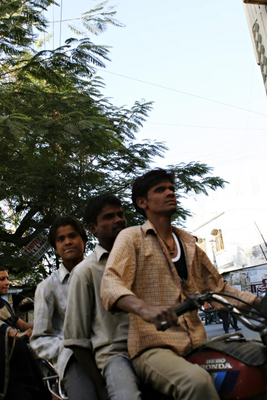 three men riding on the back of a motorcycle