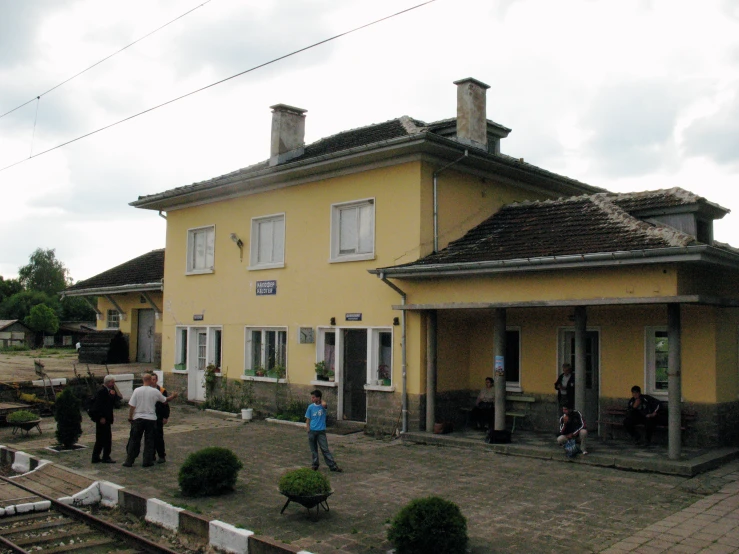 some people standing outside a house next to a rail