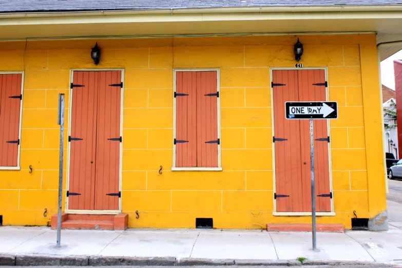 a yellow building has several windows and two directional signs