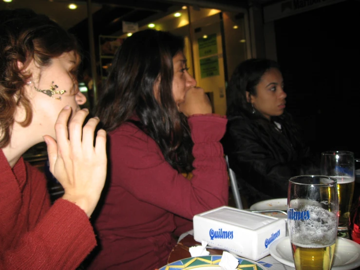 two women sitting at the table and a bottle of beer