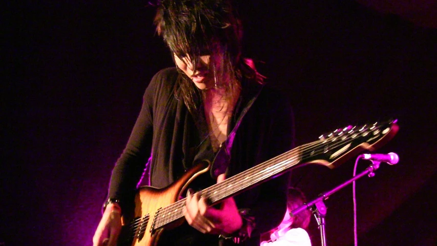 a woman with long hair plays an electric guitar