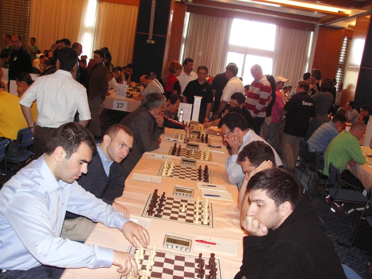 men in business suits playing chess inside an auditorium