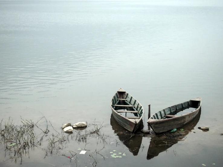 two empty rowboats tied up on the lake