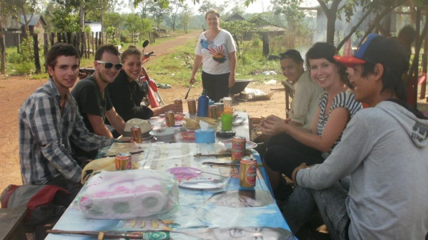 many people sitting at a picnic table eating