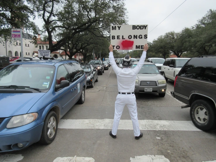 a man is holding up a sign in the middle of the road