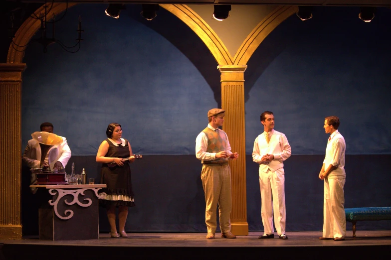 four people on stage one has a white suit