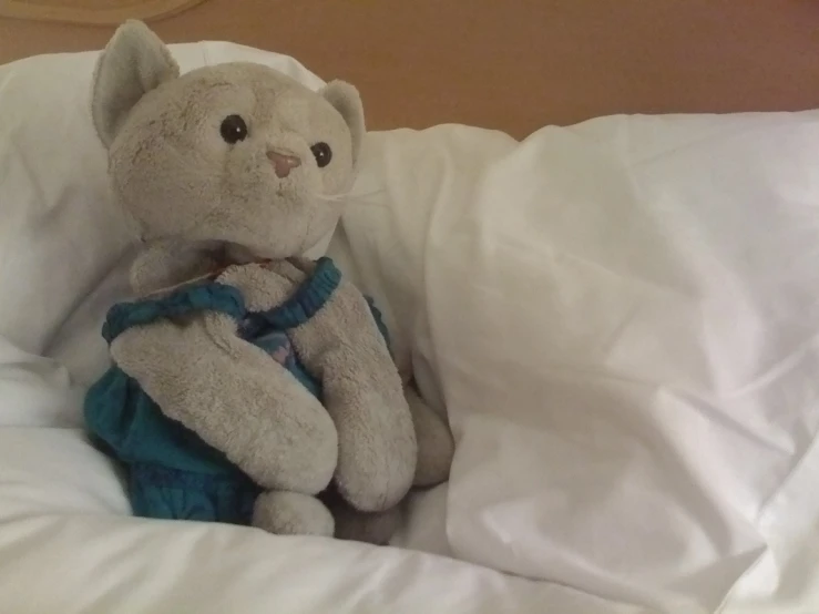 a stuffed animal on the edge of a bed