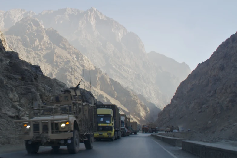 a military truck drives past military vehicles on a mountain road