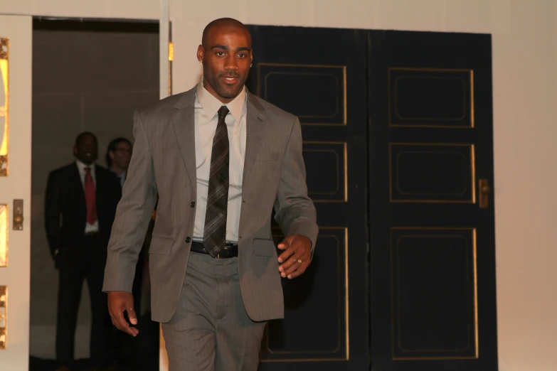 an african american man in a gray suit and tie is walking down the runway