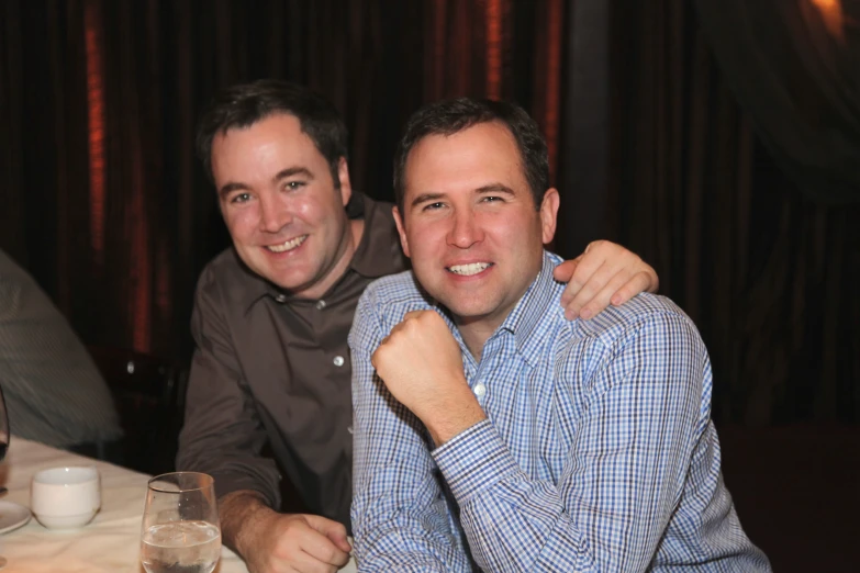 two men sitting at a table posing for the camera