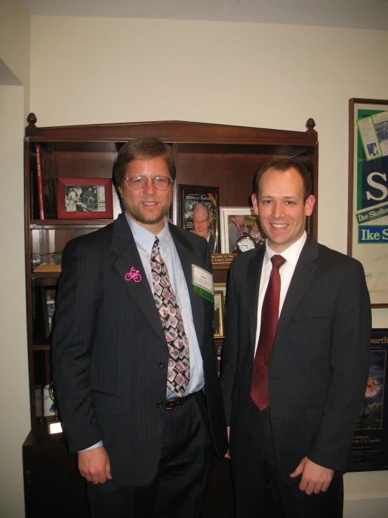 two men are dressed in suits standing next to each other