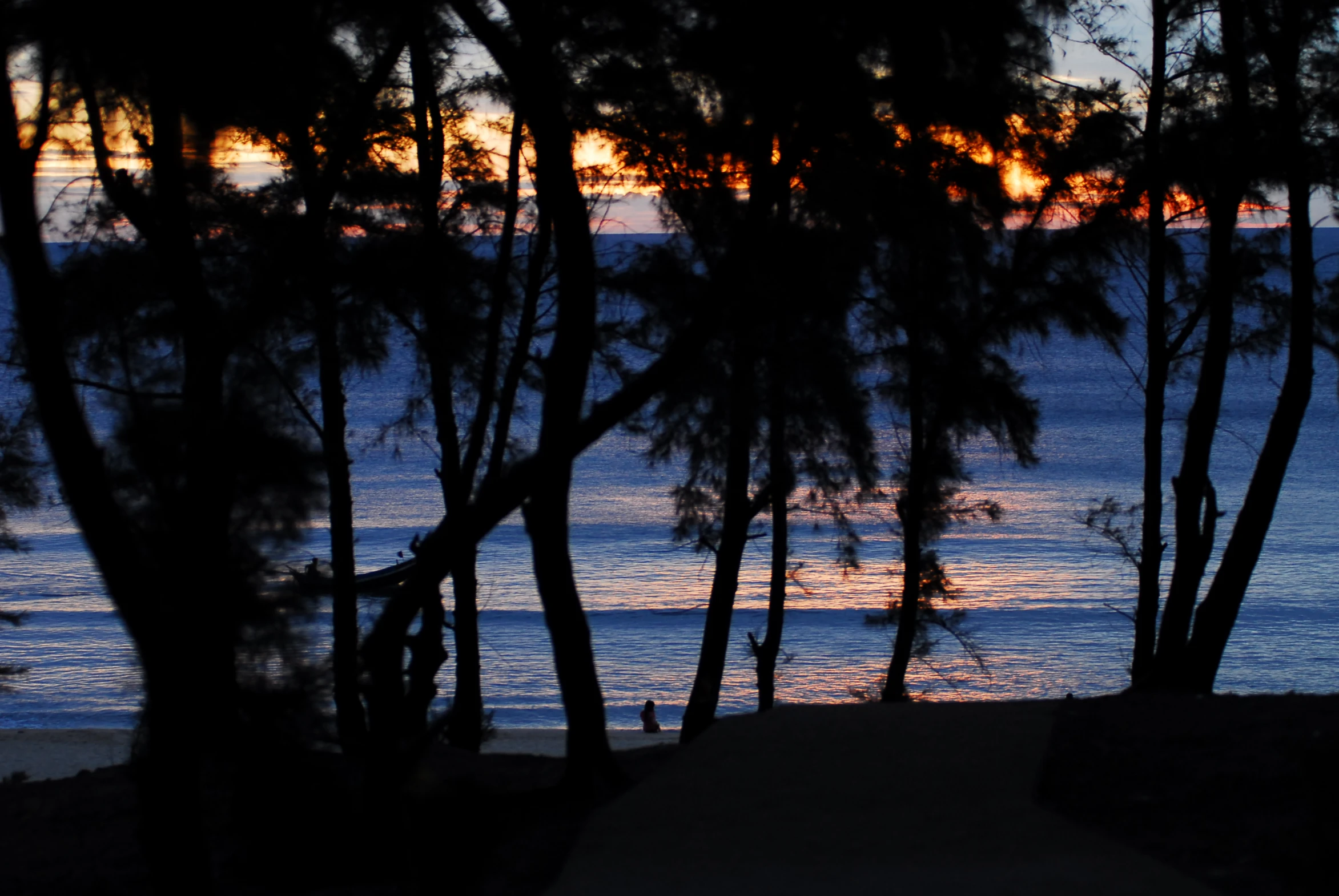 the sun is setting over the ocean in a silhouette