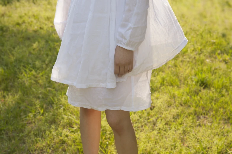 a young woman in a white dress standing on grass