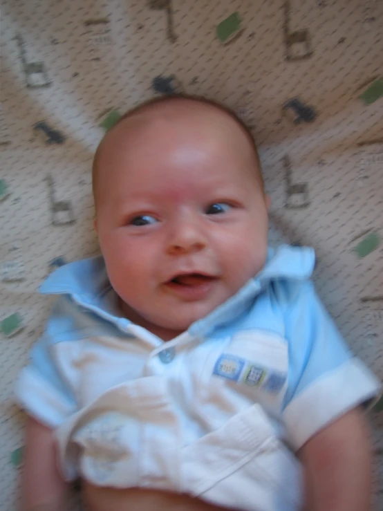 baby laying down on bed looking up at the camera