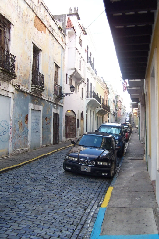 a couple of cars are parked on a narrow street
