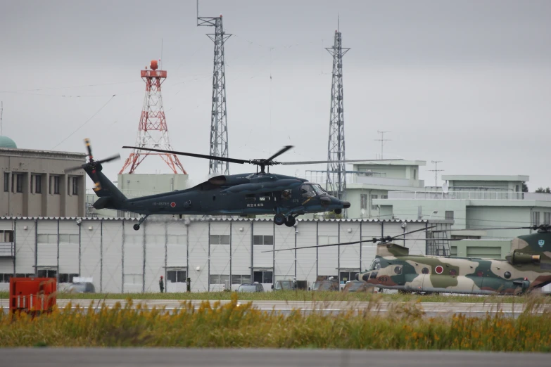 the black helicopter is parked by two other airplanes