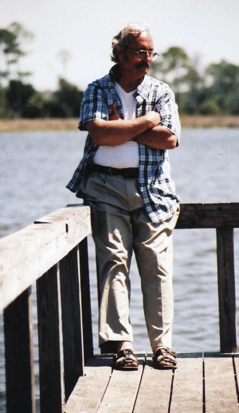 a man standing on a wooden dock near the water