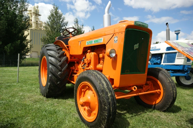 a large orange tractor sitting in the grass