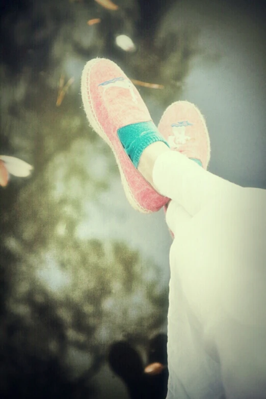 a person with pink tennis shoes standing in front of trees