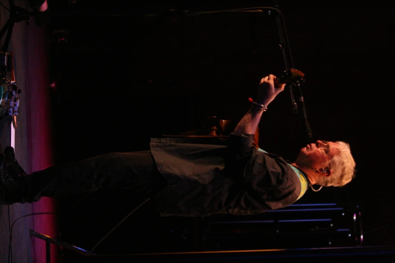 a man playing an instrument and singing in a black room