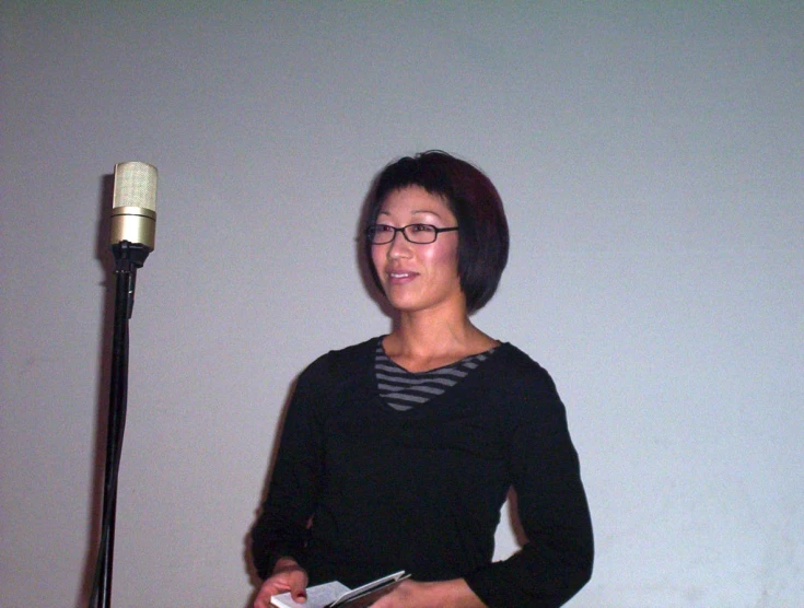 a woman standing next to a microphone holding a small remote