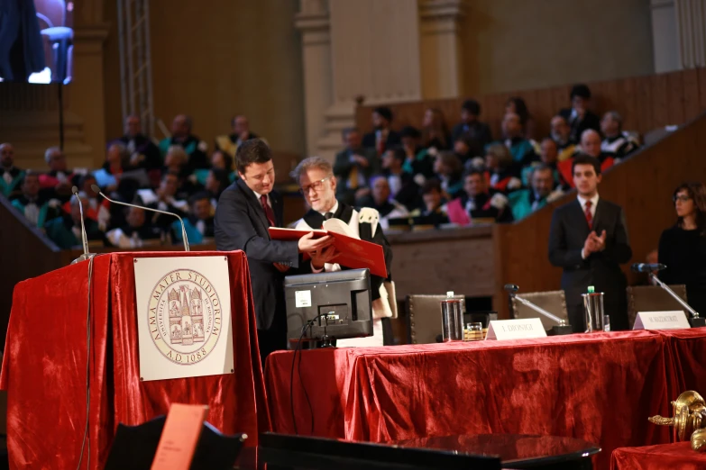 a man is standing at a podium reading from a book