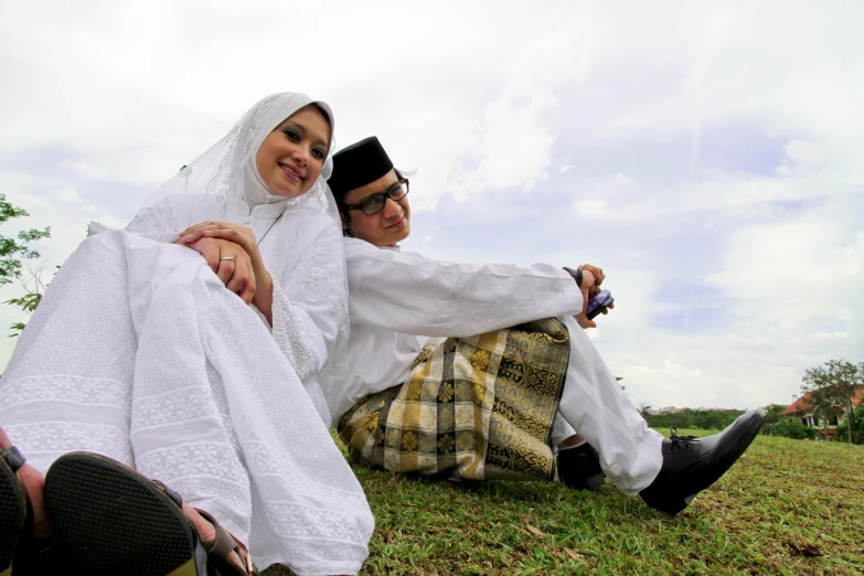 two people sit on the ground in the grass