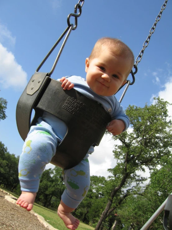 the baby is holding onto the swing and smiling