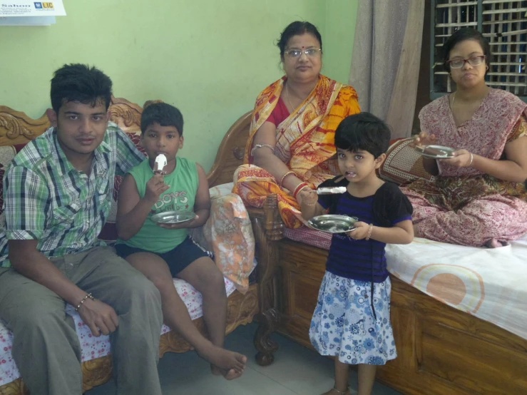 two women and a boy sitting on a bed, one of the people is eating