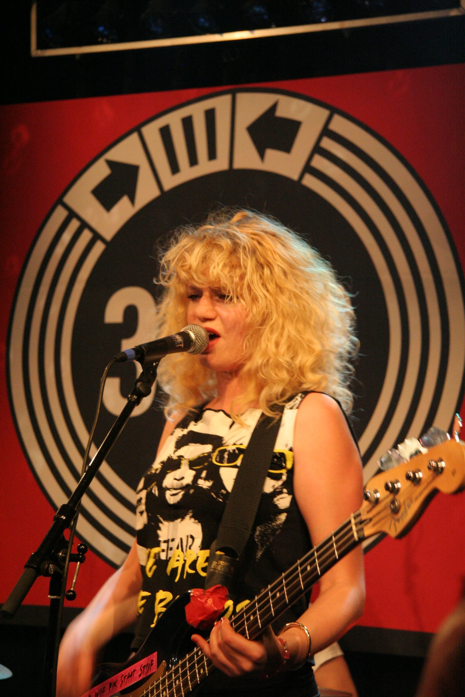 the young woman with blonde hair is singing into her guitar