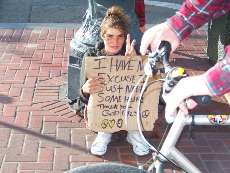 man sitting in front of a bike while giving the peace sign