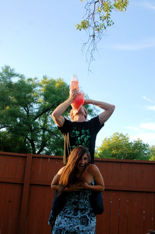 a woman hanging upside down in front of a fence