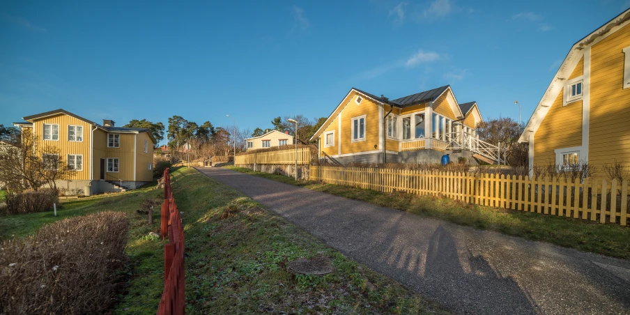 a row of houses sit on a street lined with shrubs